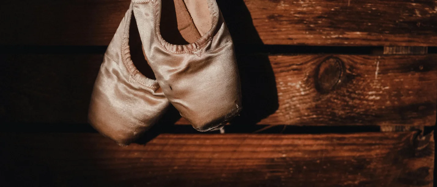 Ein Abend zur Erinnerung an die der amerikanische Tänzerin und Choreografin Isadora Duncan (Foto: unsplash | Gaelle Marcel) Zwei rosafarbene Spitzenschuhe lehnen an einer Wand.