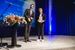 Two men in suits stand on a stage. One is the laudator, the other the award winner.