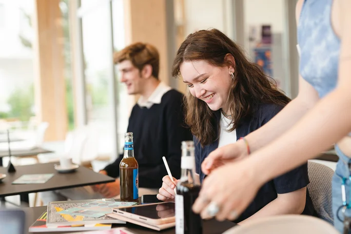 Studierende sitzen in der Mittagszeit im Café Larix.