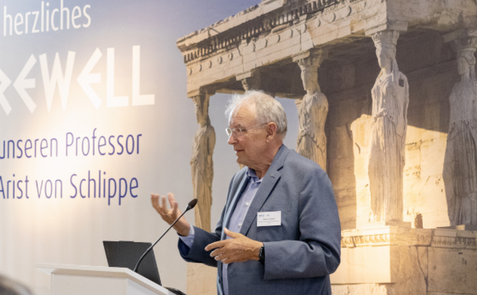 Prof. Dr. Arist von Schlippe verabschiedet sich in den Ruhestand (Foto:UW/H/WIFU-Stiftung) Ein älterer Mann steht vor einem Rednerpult.