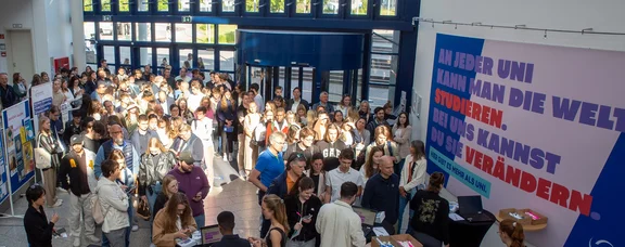 Ein große Gruppe von Personen kommt in ein Gebäude hinein.