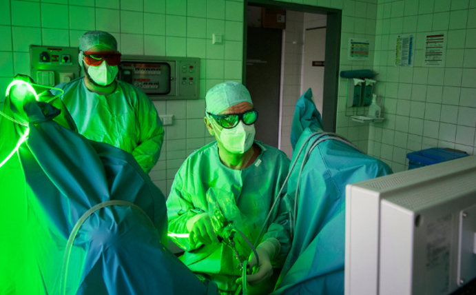 Zwei Personen sind in einem OP-Saal, der durch grünes Licht beleuchtet wird.