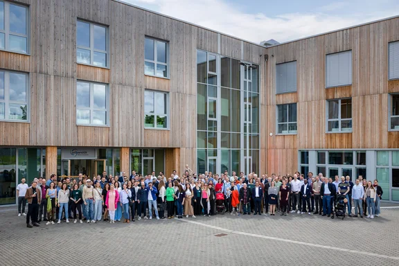 Eine Gruppe von Menschen steht vor dem Holzbau der Uni Witten/Herdecke.