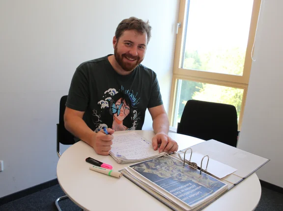 Andreas sitzt mit Notizen am Tisch