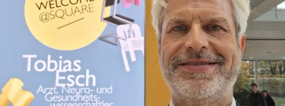 Prof. Dr. Tobias Esch steht vor einem Programmplakat