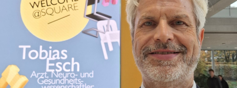 Prof. Dr. Tobias Esch an der Universität St. Gallen (Foto: privat) Prof. Dr. Tobias Esch steht vor einem Programmplakat