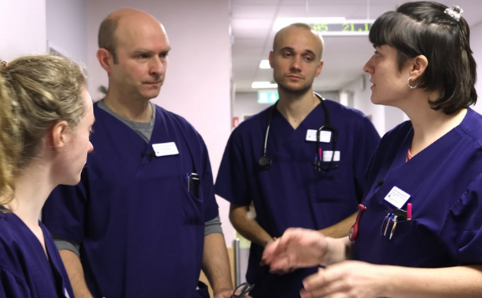 Eine Gruppe von Ärzt:innen und Medizinstudierenden in einem Krankenhausflur.