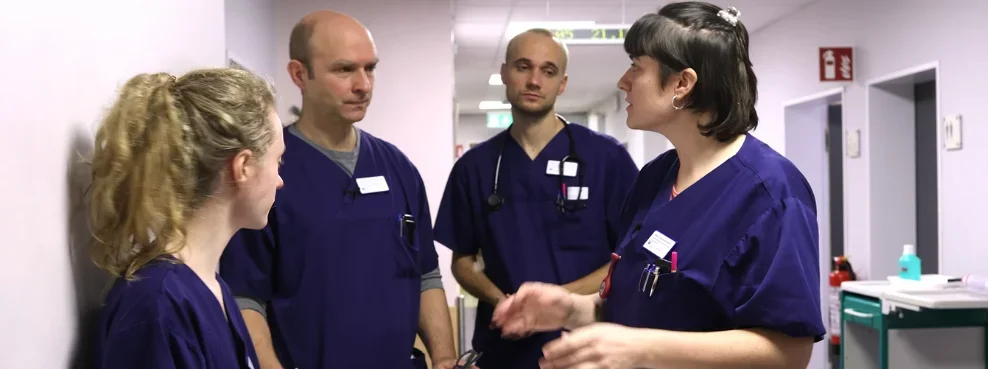Eine Gruppe von Ärzt:innen und Medizinstudierenden in einem Krankenhausflur.