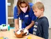 A female student and a boy look at his soft toy.