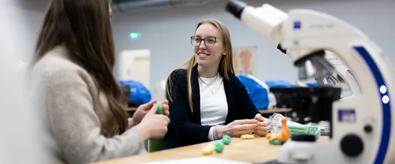 Zwei Studentinnen am Tisch mit Mikroskop 