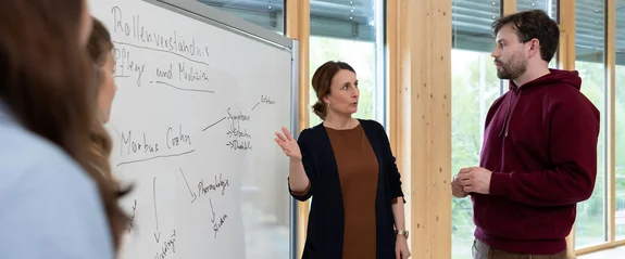 Eine Professorin am Whiteboard im Austausch mit den Studenten