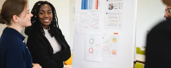 Bewirb dich für den Studiengang PPÖ – Philosophie, Politik und Ökonomik (B. A.) an der UW/H. (Foto: UW/H | Johannes Buldmann) Drei junge Menschen stehen vor einem Flipchart.