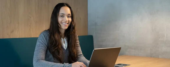 A woman sits with a laptop in a seating area