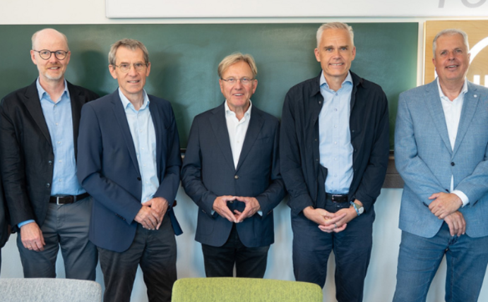 Seven men stand next to each other and smile into the camera.
