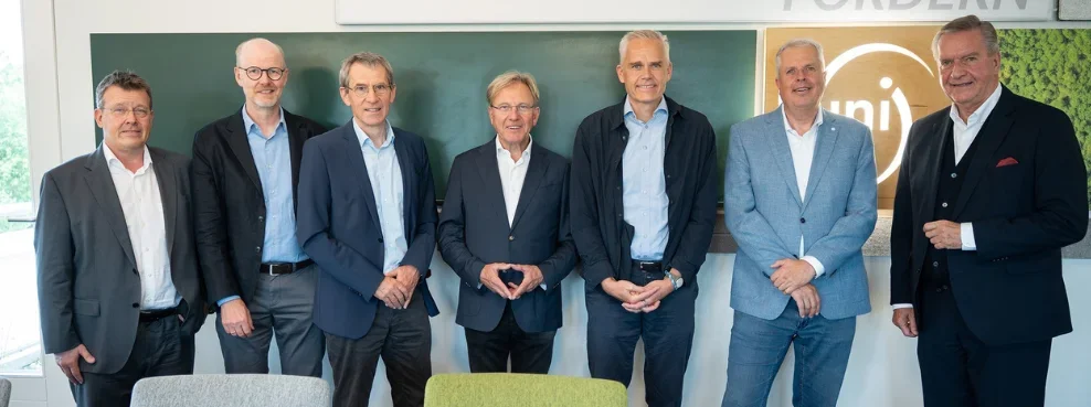 Seven men stand next to each other and smile into the camera.