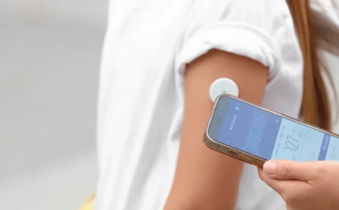 A child with diabetes has their blood sugar measured using a smartphone and a Bluzucker sensor