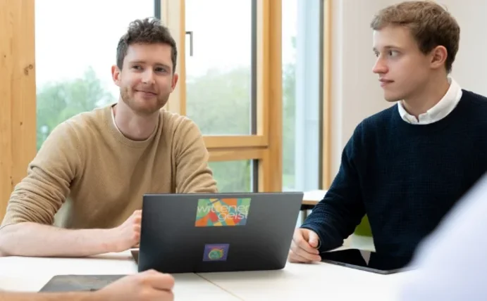 Einige Studierende sitzen am Tisch und unterhalten sich.