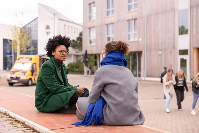 Zwei Studierende unterhalten sich auf dem Außengelände der UW/H