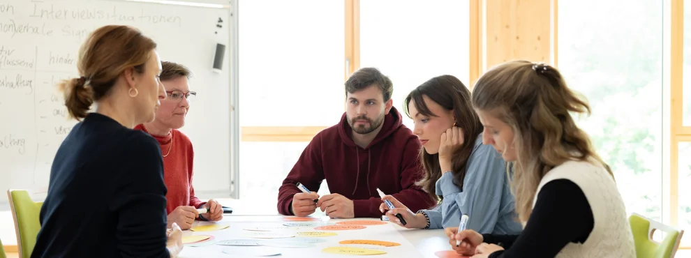 Professorin und Studierende sitzen an einem Tisch zum Dialog