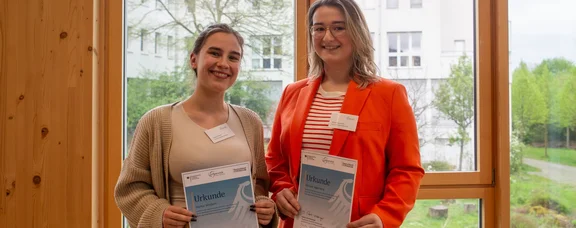 Two scholarship recipients are holding up their donation certificates.