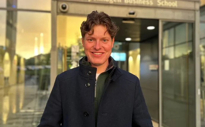 Porträtbild von Moritz Krauss vor einem Gebäude mit Glastüren.