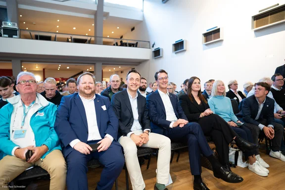 Viele Menschen sitzen in einem Saal.