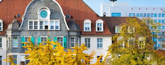 Helios Universitätsklinikum Wuppertal - Campus Barmen (Foto: Michael Mutzberg) Außenansicht eines Krankenhausgebäudes. Im Vordergrund sind herbstliche Bäume.