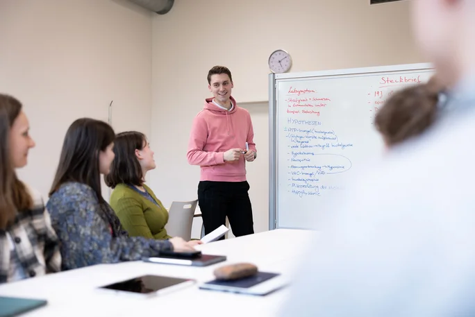 Human medicine students discuss a case on the whiteboard