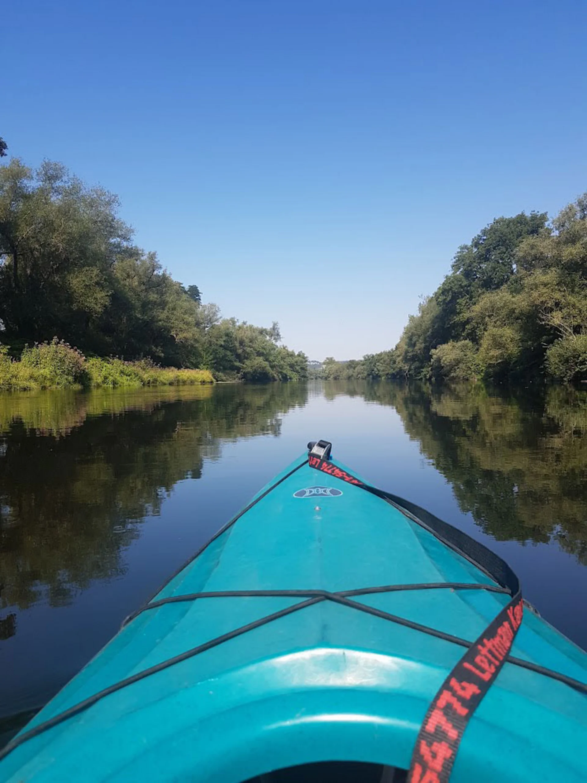 Kayak trip on the Ruhr (Photo: Private) A photo taken from the bow of a kayak gliding down a river. There are trees on the left and right.