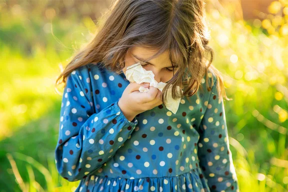 A girl sneezes and holds a handkerchief to her nose.