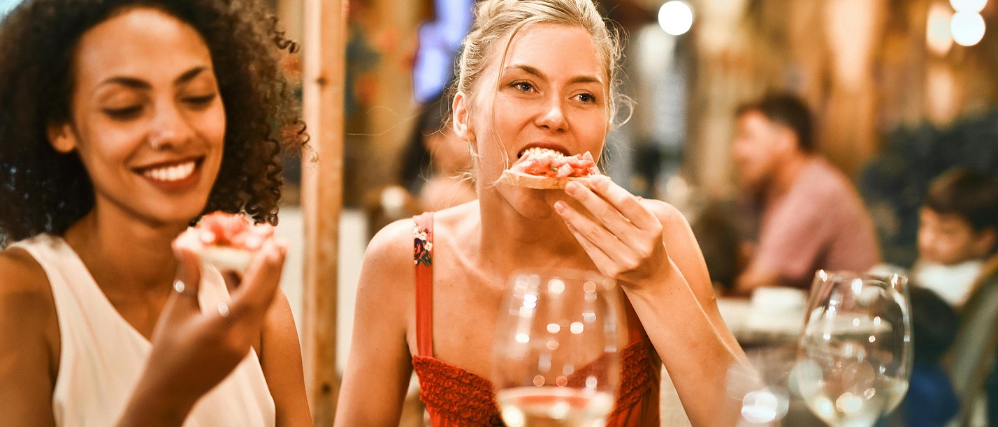 Two women having dinner. They are sitting at a restaurant table.