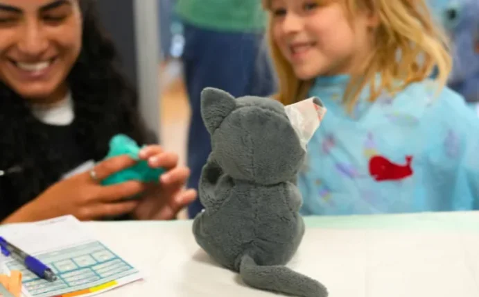 Eine Studentin und ein Mädchen bereiten eine Plüschkatze für den OP vor.