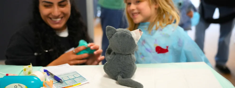 Eine Studentin und ein Mädchen bereiten eine Plüschkatze für den OP vor.