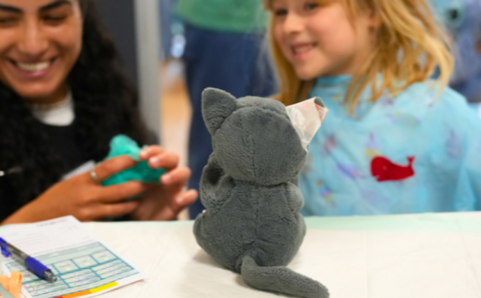 Eine Studentin und ein Mädchen bereiten eine Plüschkatze für den OP vor.