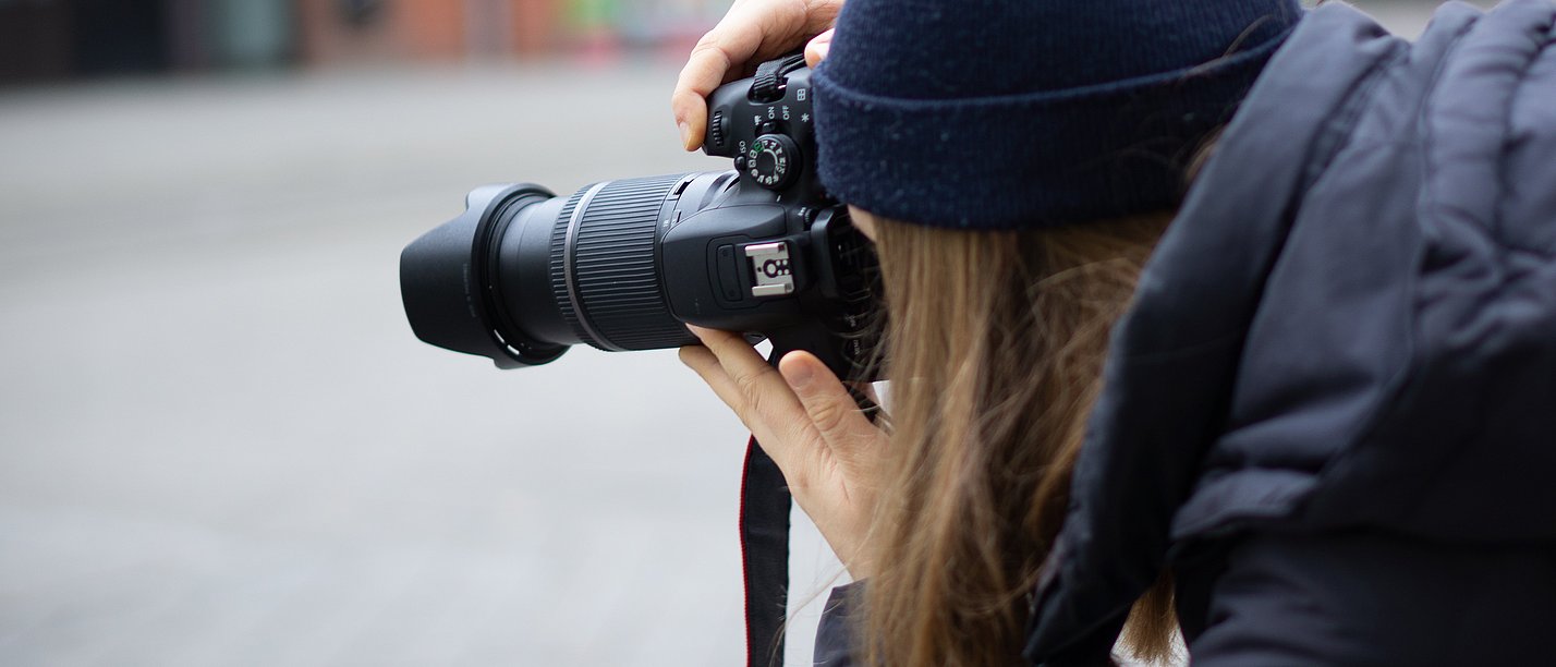 Studierende der UW/H versteigern ihre Fotografien aus Witten für einen guten Zweck (Foto: UW/H) Eine Frau macht Fotos mit einer Kamera.