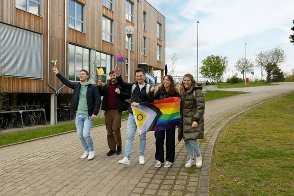 Diversity in action (Photo: UW/H | Michael Schwettmann) Students are walking across the campus waving pride flags.