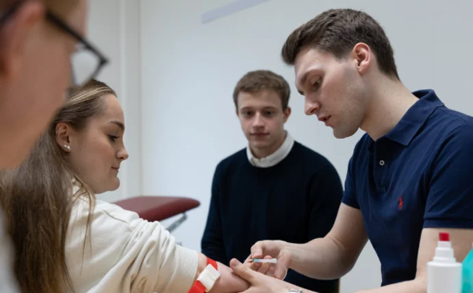 Medizinstudierende, die eine Blutentnahme üben.