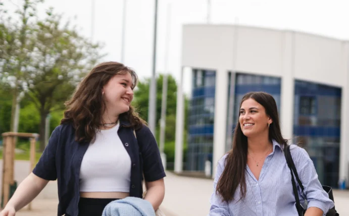 Three students are walking across the campus of Witten/Herdecke University, beaming with joy.