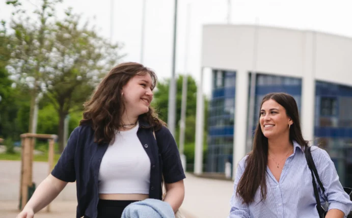 Drei Studierende laufen freudestrahlend über den Campus der Uni Witten/Herdecke.