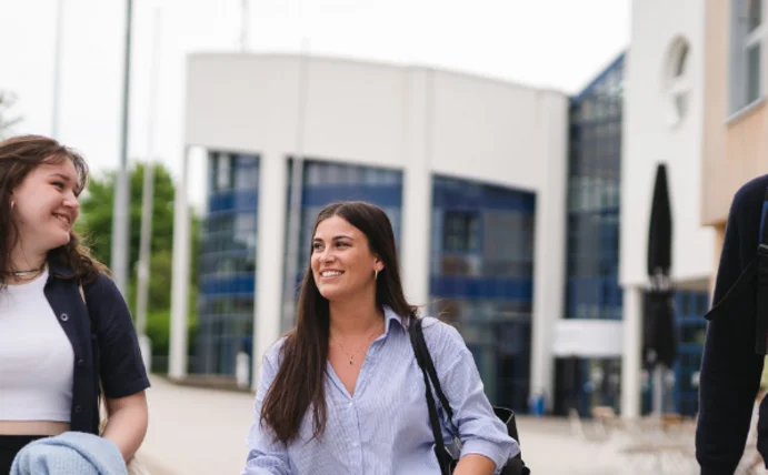 Absolvent:innen der Universität Witten/Herdecke fühlen sich sehr gut auf die berufliche Praxis vorbereitet (Foto: UW/H | Johannes Buldmann) Drei Studierende laufen freudestrahlend über den Campus der Uni Witten/Herdecke.