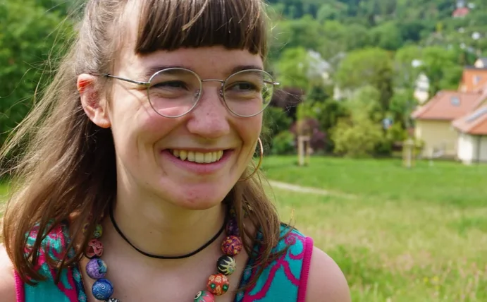 Foto von Emmi Mentzel. Im Hintergrund sind eine grüne Wiese und Bäume.