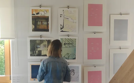 Ownership and Sharing. A series of talks (Photo: UW/H) A person, seen from behind, is looking at unframed prints hanging on the wall