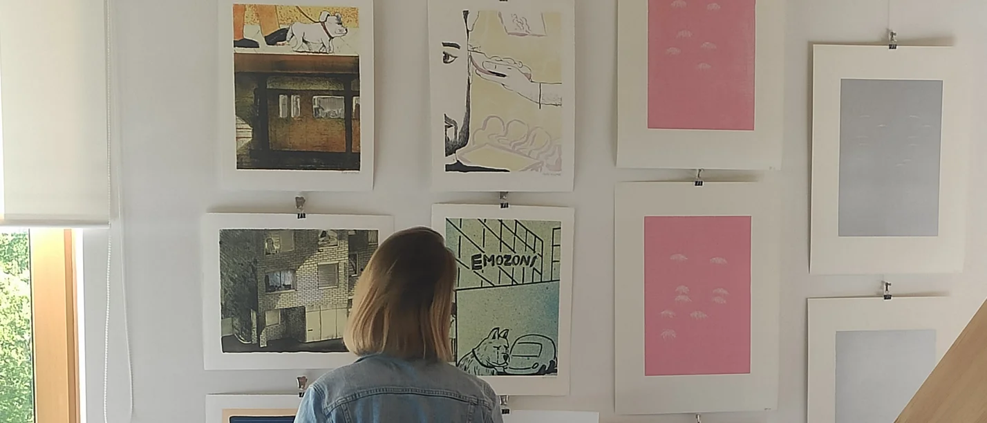 Ownership and Sharing. A series of talks (Photo: UW/H) A person, seen from behind, is looking at unframed prints hanging on the wall