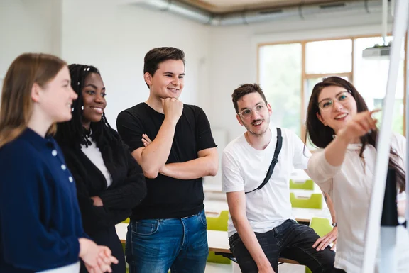 Bachelor Studenten stehen vor einem Flipchart und besprechen ein Thema