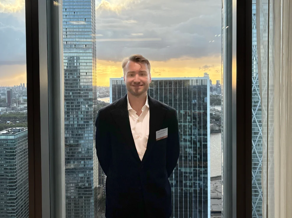 Niklas Kaminski steht vor einer Fensterfront mit Hochhäusern im Hintergrund.