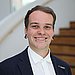 Ein junger Mann mit Piercings im Gesicht lächelt freundlich in die Kamera.