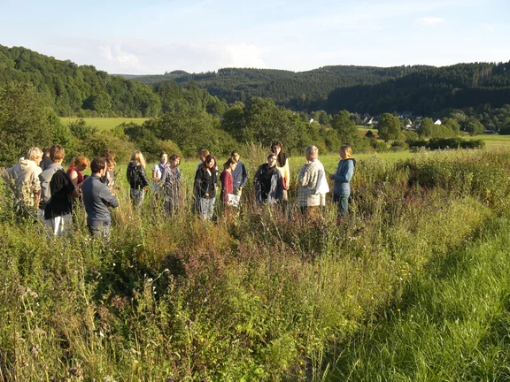 Eine Gruppe Menschen steht auf einer Wiese.