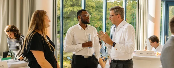 We have a network (Photo: UW/H | Michael Kotowski) A photo of three people standing side by side and chatting.