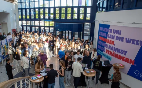 Komm zum Infotag – dem Tag der offenen Tür an der UW/H. (Foto: UW/H | Michael Schwettmann) Ein große Gruppe von Personen kommt in ein Gebäude hinein.