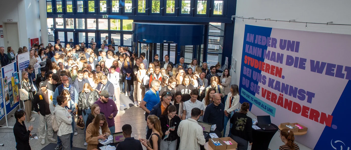 Ein große Gruppe von Personen kommt in ein Gebäude hinein.